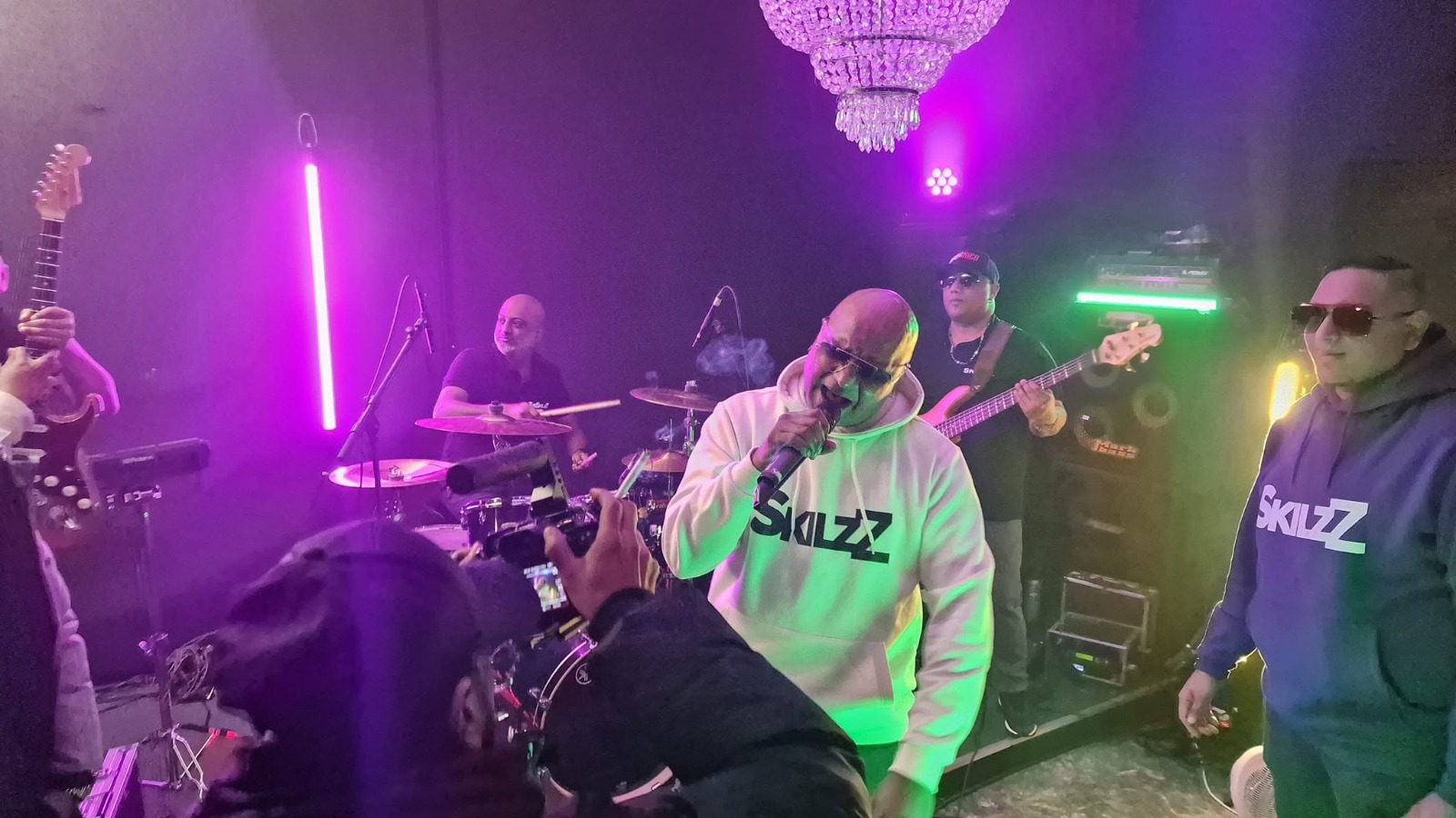 Skilzz band live met zanger, drummer en bassist onder neonlicht
